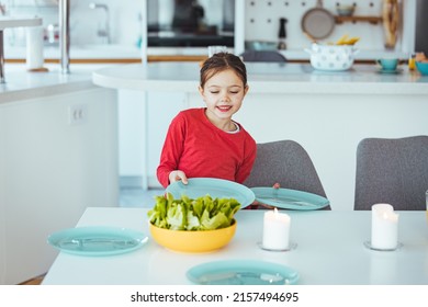 Little Girtl Helping Mother To Set The Table For Dinner, Carrying The Plates, Kitchen Interior, Cropped, Copy Space. Smiling Girl Setting Table.