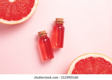 Little Glass Vial Of Aroma Essential Oil Wich Grapefruit Fresh Slice. Flat Lay, Top View Face Serum In Bottle On Pink Table. SPA Relax, Face Skin Care And Body Treatment.