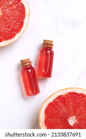 Little Glass Vial Of Aroma Essential Oil Wich Grapefruit Fresh Slice. Flat Lay, Top View Face Serum In Bottle On Marble Table. SPA Relax, Face Skin Care And Body Treatment.