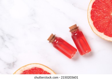 Little Glass Vial Of Aroma Essential Oil Wich Grapefruit Fresh Slice. Flat Lay, Top View Face Serum In Bottle On Marble Table. SPA Relax, Face Skin Care And Body Treatment.