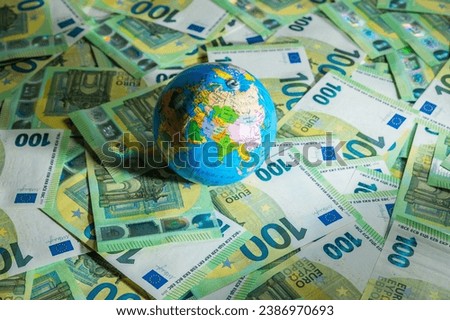 A little globe map lying on an assortment of euro money bills