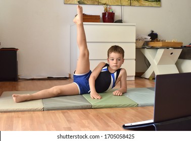 El niño pequeño gimnasta se está entrenando en línea con una laptop en casa