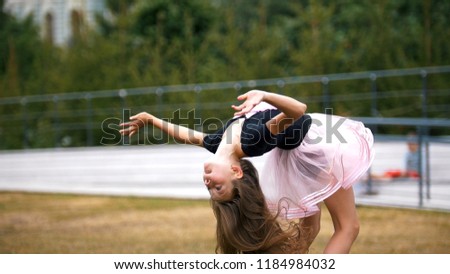 Little gymnastic girl is doing bridge exercise in the park
