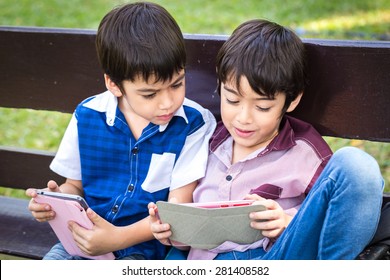 Little handsome boy looking on ipad tablet and playing game at park