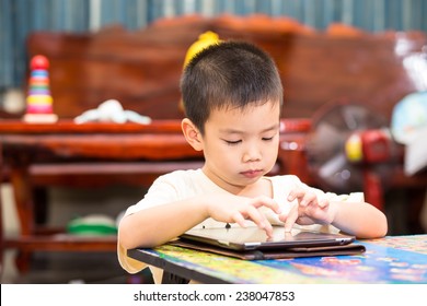 Little Handsome Boy Touch On Ipad Tablet And Playing Game At Home