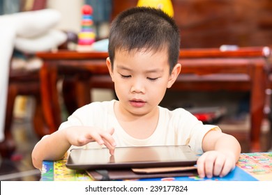 Little Handsome Boy Touch On Ipad Tablet And Playing Game At Home