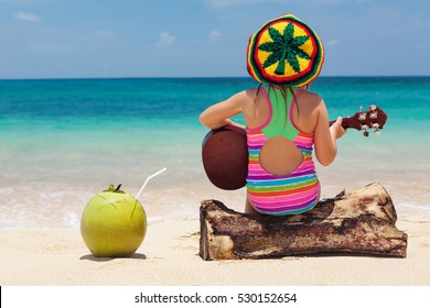 Little happy baby in rastaman hat have fun, play reggae music on Hawaiian guitar, enjoy relaxing on ocean beach. Children healthy lifestyle. Travel, family activity on tropical island summer holiday