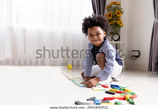 Little happy black people African\
American child playing with toys kid in the living\
room.\
