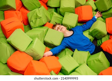 Little Happy Boy Enjoys Relaxing In Dry Pool Of Soft Cubes. Children's Entertainment In Play Center.