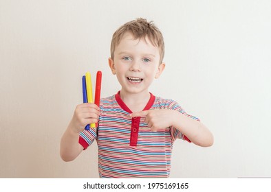 Little happy boy holds colorful markers for drawing