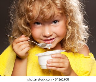 Little happy child eating yogurt