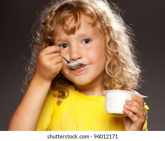 Little happy child eating yogurt