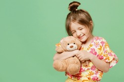 Little Happy Child Kid Girl 6-7 Year Old Wear Casual Clothes Have Fun Hold Hug Teddy Bear Plush Toy Isolated On Plain Pastel Green Background Studio Portrait Mother's Day Love Family Lifestyle Concept