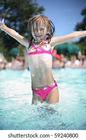 Little happy girl enjoys summer day at the swimming pool.