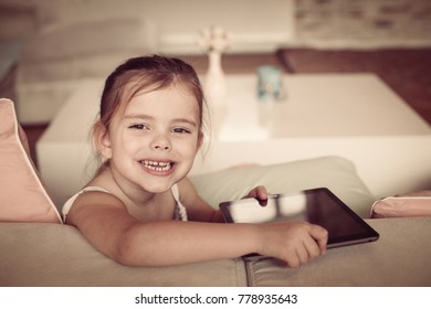 Little Happy Girl At Home Using IPod. Looking At Camera.