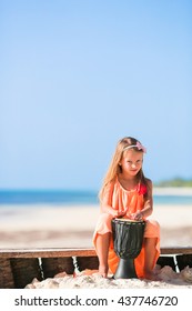 Little Happy Girl Playing African Drums. Adorable Kid Having Fun With National African Drums On White Beach