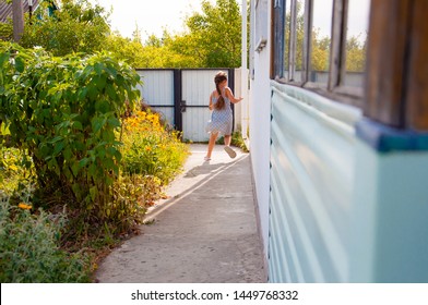 Little Happy Girl Running Around The Corner Of A House In A Summer Village