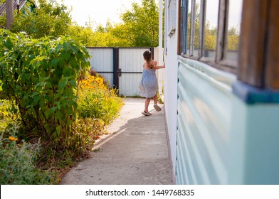 Little Happy Girl Running Around The Corner Of A House In A Summer Village