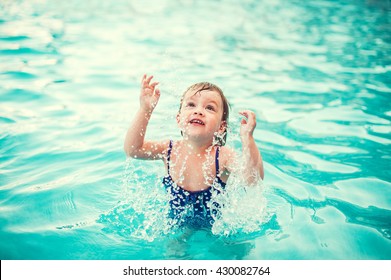 Little Happy Girl In Swimming Pool. Kid Splashing On Pool