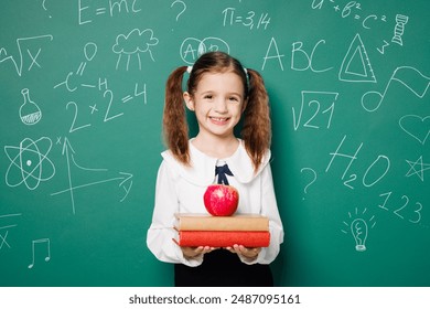 Little happy school girl 7-8 years old pony tails wear white shirt uniform hold books red apple look camera isolated on green blackboard background studio. Childhood kids education lifestyle concept - Powered by Shutterstock