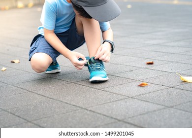 A Little Healthy Asian Schoolboy Putting On His Running Shoes By Himself In The Playground. Life Skills, Self-care, Montessori Child, Comfortable Kids Shoes, Sport Day, Outdoor Fun, Get Ready Concept.