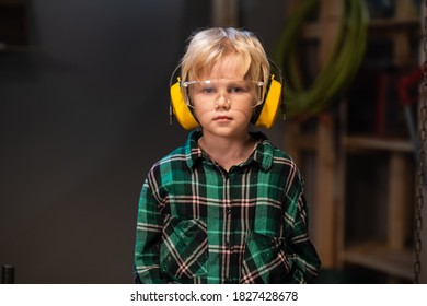 little helper of a carpenter or Builder, blond hair in a shirt, protective glasses and headphones, close-up portrait