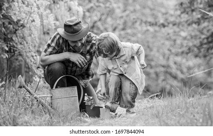 Little helper in garden. Planting flowers. Make planet greener. Growing plants. Take care of plants. Boy and father in nature with watering can. Gardening tools. Dad teaching little son care plants.