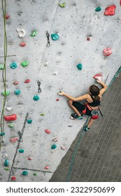 Little hiker. Portrait of active teen girl climbing the grey rock wall. Top view. Sport weekend action in adventure park. Active lifestyle concept - Shutterstock ID 2322950699