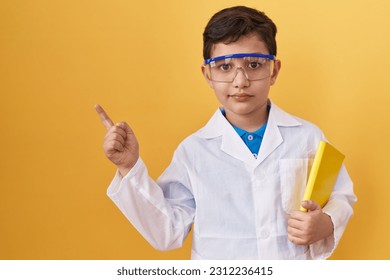 Little hispanic boy wearing scientist glasses smiling happy pointing with hand and finger to the side  - Powered by Shutterstock