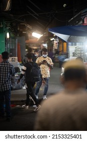 Little India, Singapore: May 3 2022: A Person Standing Still With His Phone As The World Around Him Passed By