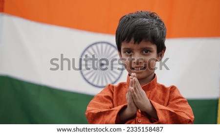 Little Indian boy celebrate the Auspicious Day - Independence Day Or Republic Day, Indian Model. Charming boy standing in a namaste position with a tricolor background, facing towards the camera