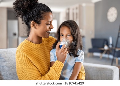 Little indian girl making inhalation with nebulizer with lovely mother. Woman makes inhalation to a sick child while embracing her. Mom helping daughter with cold and flu to inahale nebuliser aerosol. - Powered by Shutterstock