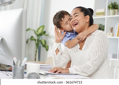 Little Indonesian Boy Kissing His Mom, Who Is Working In Office