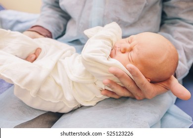 Little Infant Newborn Child In Maternity Hospital On His Fathers Arms. Man Holding Sleeping Baby. Lifestyle