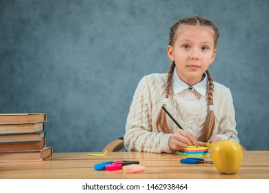 Little, Inquisitive And Cute Girl Is Watching At The Camera With Almond-shaped Eyes And Raised Brows. Two Neat Braids. Eager To Learn.