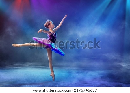 little Japanese ballerina dances on stage in a lilac tutu on pointe shoes classical ballet.