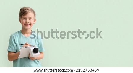 Little journalist with microphone and notebook on light color background with space for text