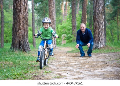 Little Kid Boy Of 4 Years And His Grand Father In Summer Forest With A Bicycle. Grandpa Teaching His Boy. Man Happy About Success. Child With Helmet. Safety, Sports, Leisure With Kids Concept.