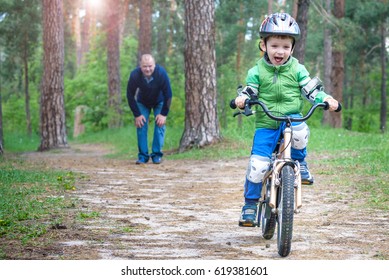 Little Kid Boy Of 4 Years And His Father Or Granfather In Summer Forest With A Bicycle. Dad Teaching Riding His Son. Child With Helmet. Safety, Sports, Leisure With Kids Concept.