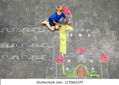 Little kid boy drawing knight castle   fortress and colorful chalks  Happy preschool child having fun and creating chalk picture  Creative leisure for kids   children in summer