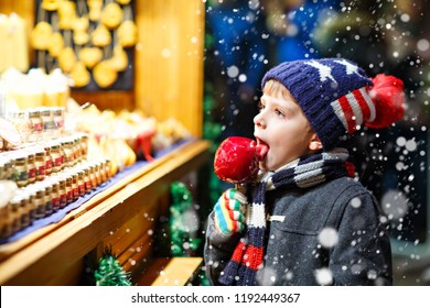 Little kid boy eating sugar apple sweets stand on Christmas market