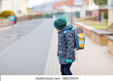 Little Kid Boy With Eye Glasses Walking From The School. Child On A Street. Preschooler Wearing Warm Spring, Autumn Or Winter Clothes, Glasses And Backpack. Happy Student Or People. Education Concept