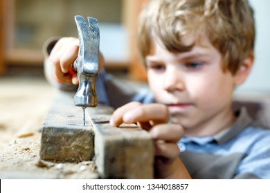 Little kid boy helping with toy tools on construction site. Funny child of 6 years having fun on building new family home. Kid with nails and hammer helping father to renovate old house.