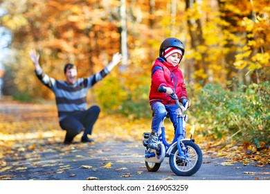 Little Kid Boy Learning Moving On Bicycle. His Father Teaching His Son Biking. Happy Man And Child. Active Family Leisure. Child With Helmet On Bike. Safety, Sports, Leisure With Kids Concept.