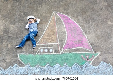 Little kid boy as pirate ship sailingboat picture painting and colorful chalks asphalt  Creative leisure for children outdoors in summer  Child and captain hat   binoculars