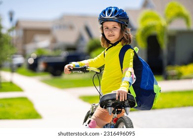 Little kid boy riding a bike in summer park. Child drive a bike on a driveway outside. Kid riding bikes in the city wearing helmets. Child on bike outdoor. Kid bicycling bike on american neighborhood.