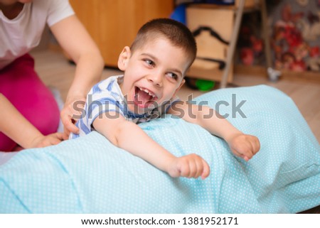 little kid with cerebral palsy has musculoskeletal therapy by doing exercises in body fixing. Load on hands,cheerful boy with disability at rehabilitation center for kids with special needs