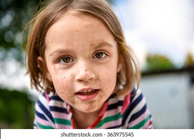 Little Kid With Dirty Face From Playing Outside In The Dirt And Mud. Games In The Nature, Healthy Children