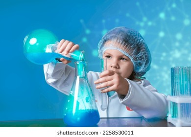 Little kid doing experiments with blue liquid. Cute child wants to become a doctor. Pretty child in white medical robe holds glass flasks with blue liquid on indigo background with hospital symbol. - Shutterstock ID 2258530011