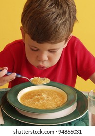 Little Kid Eating A Soup In A Kitchen.